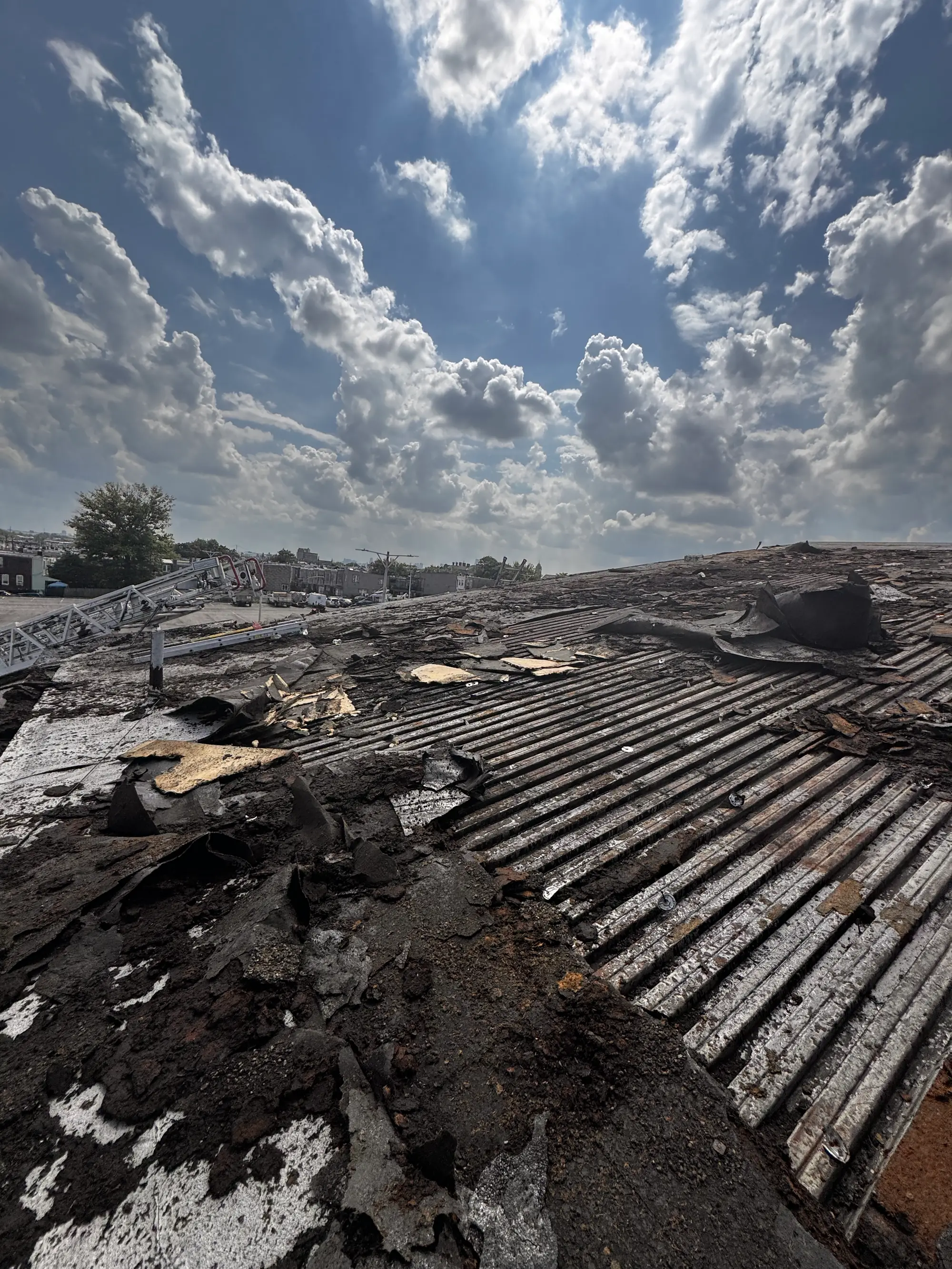Fire and storm debris spread across a commercial roof with the city skyline behind