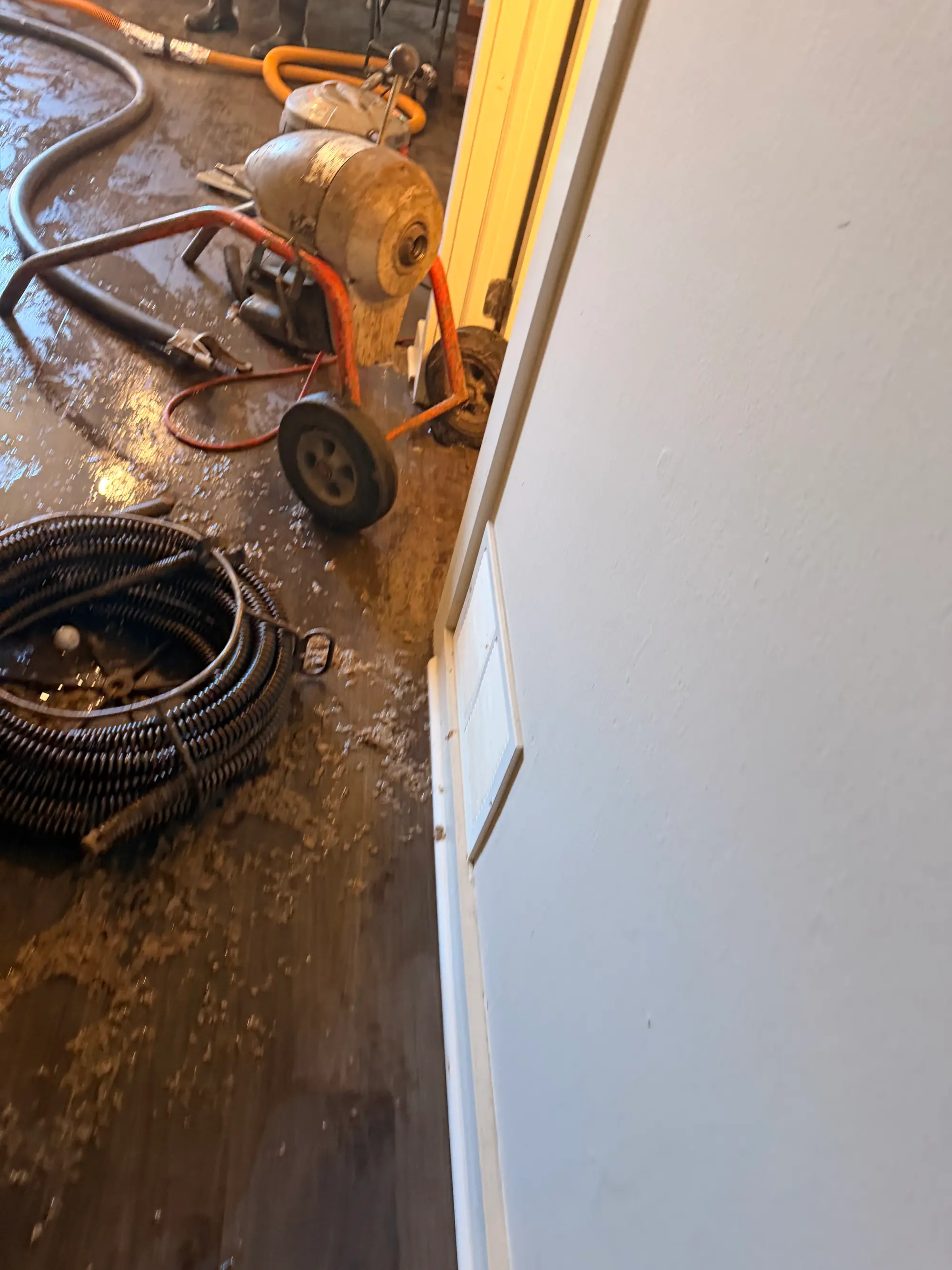 Drain snake and hoses on the floor during a drain backup and water cleanup