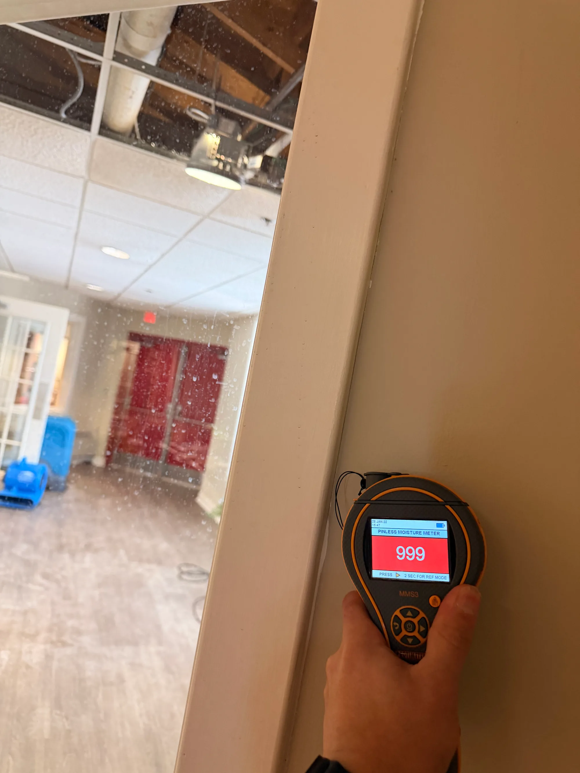 Moisture meter at its maximum reading on an opened ceiling after a water leak