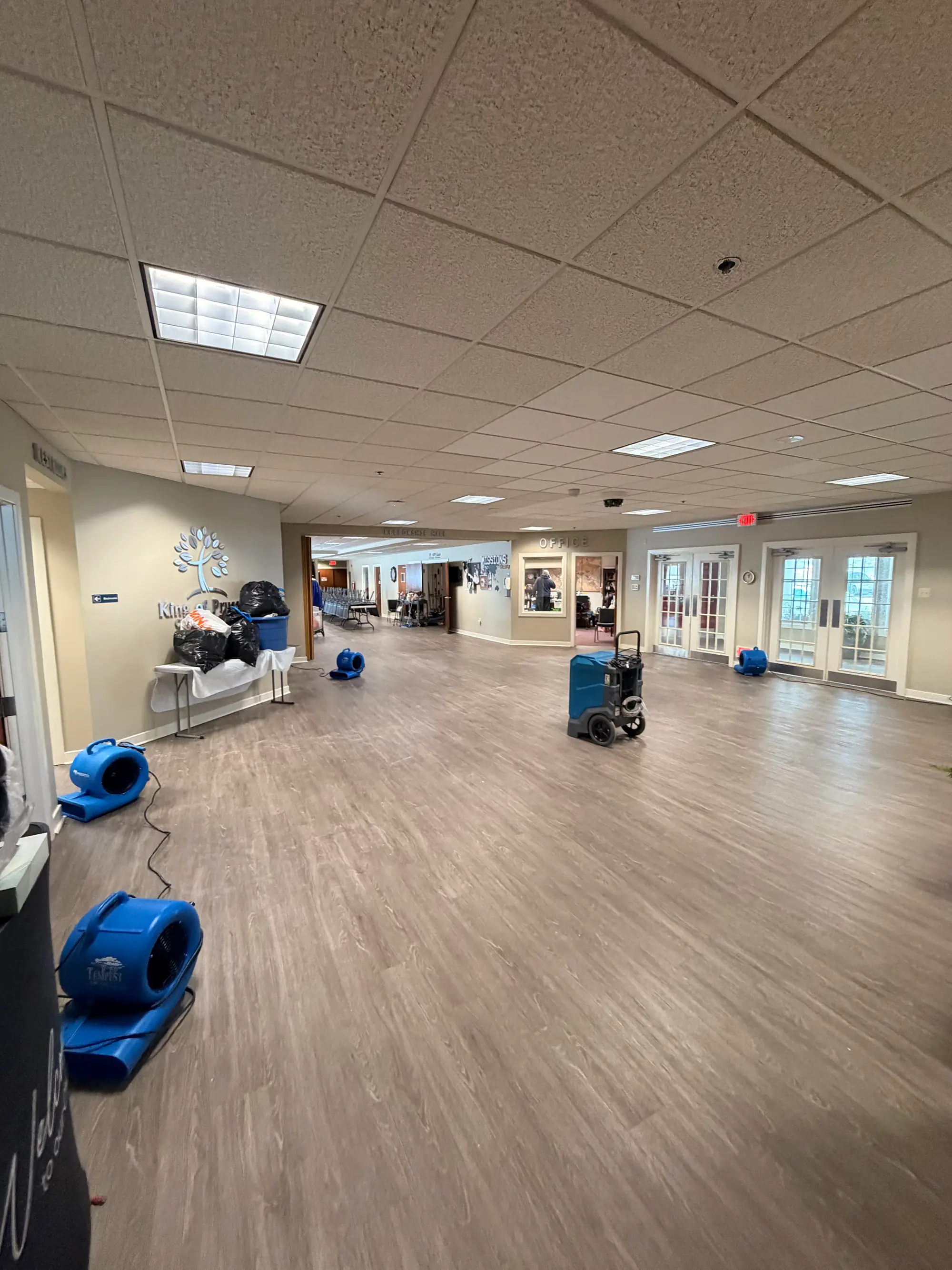 Blue air movers drying an office lobby during commercial water damage restoration