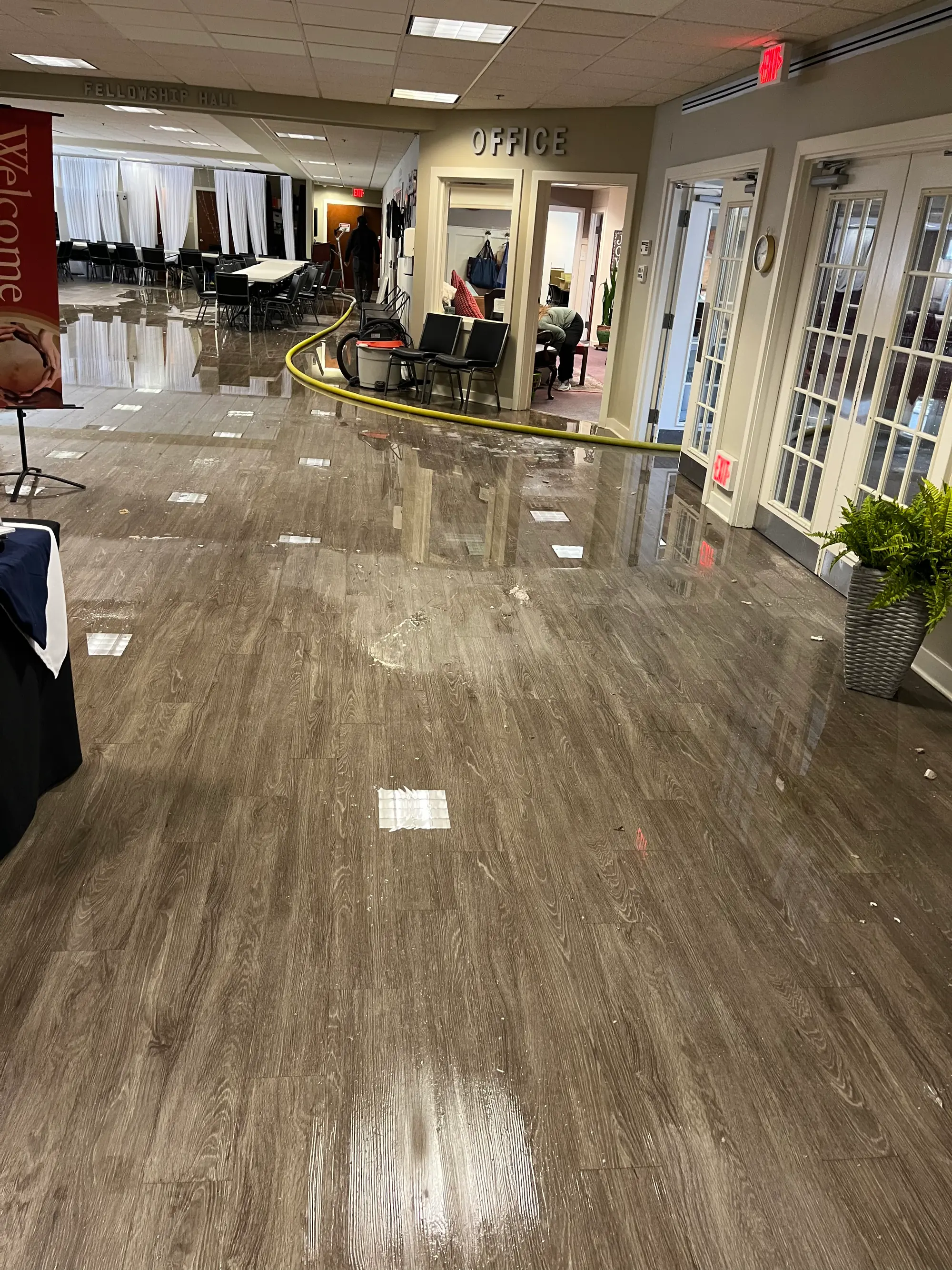 Wet office lobby floor with an extraction hose during commercial water cleanup