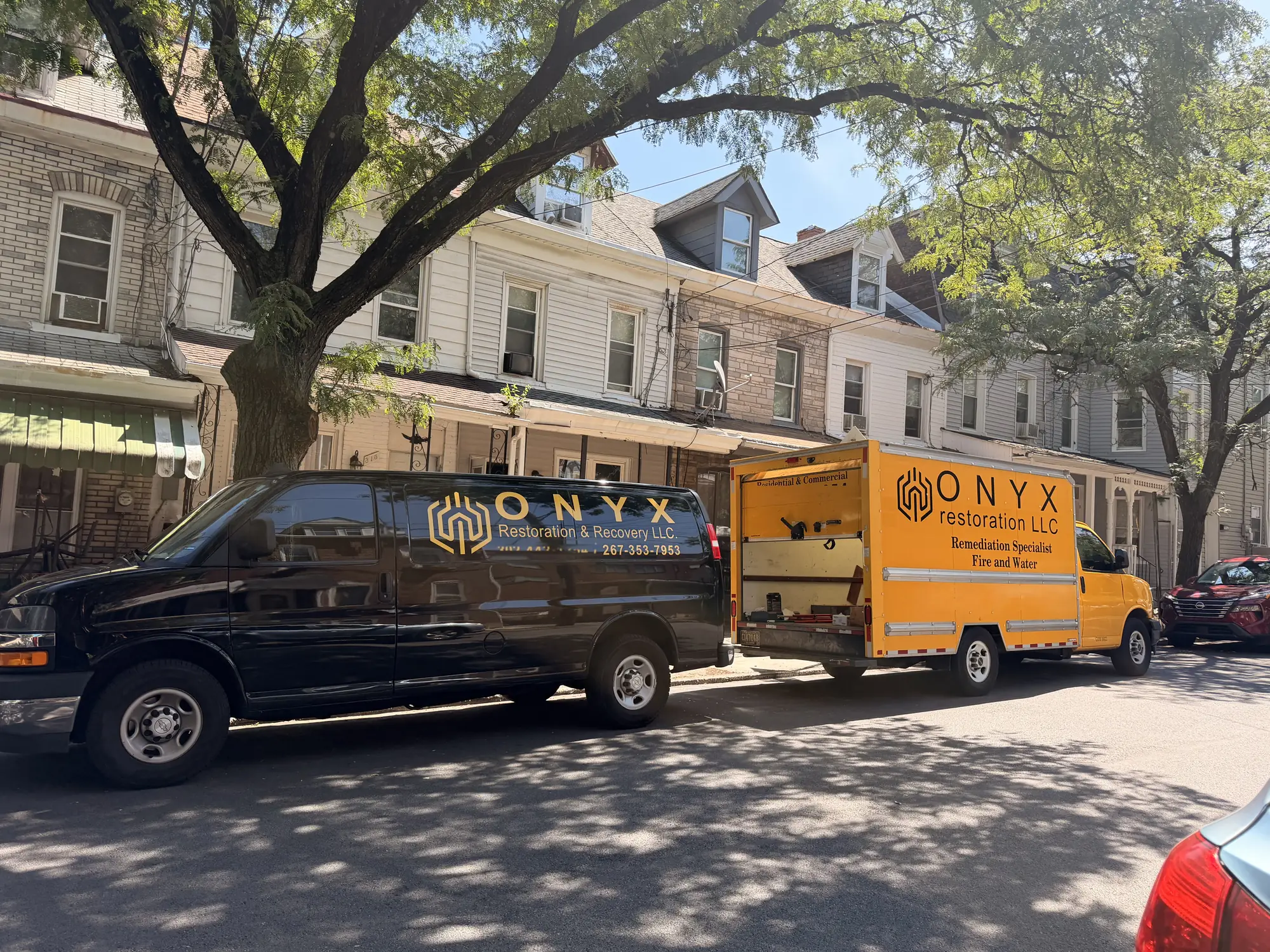 Two Onyx Restoration & Recovery vehicles parked on a residential Philadelphia street