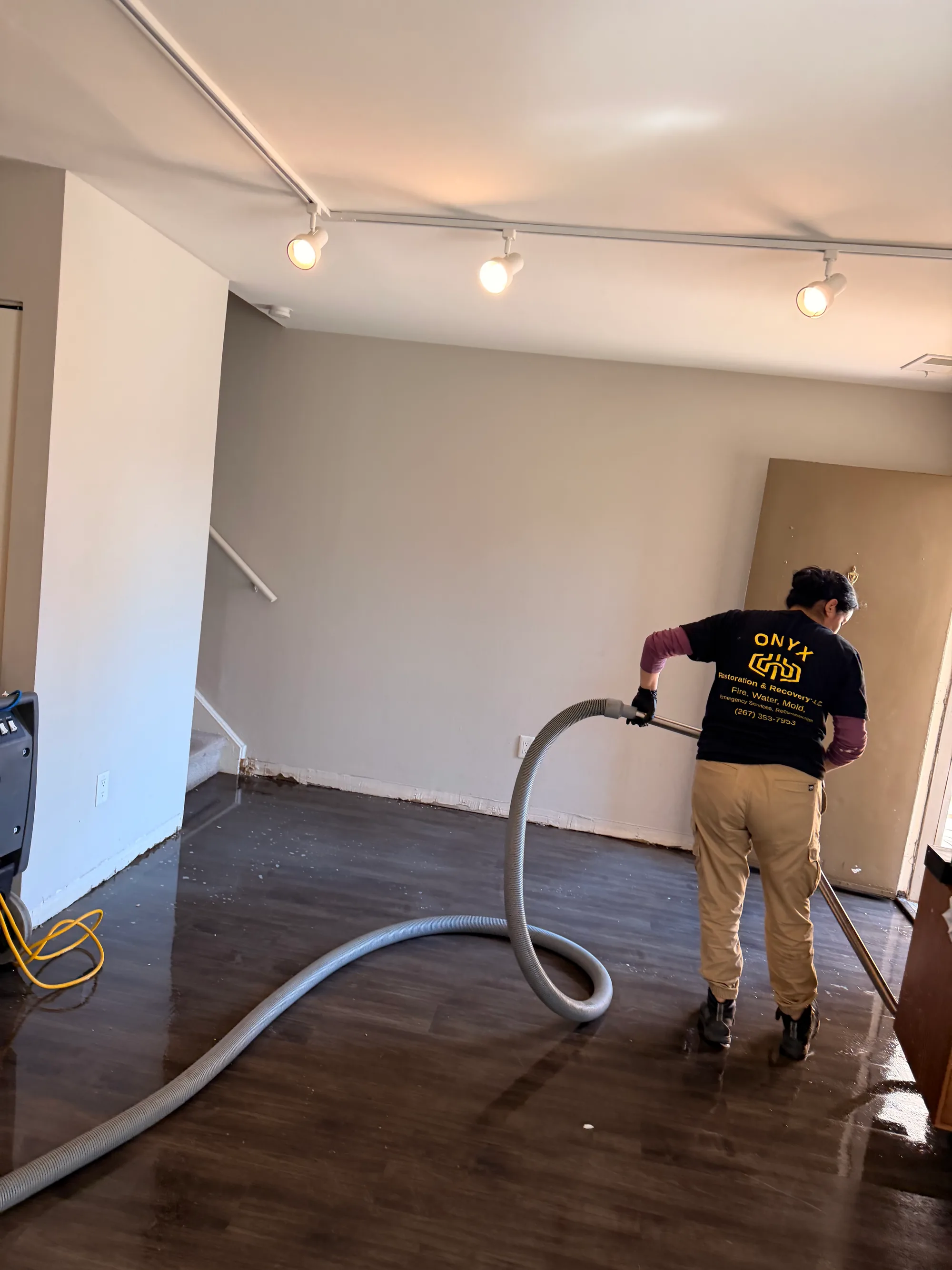 Technician extracting water from a hardwood floor during water damage restoration