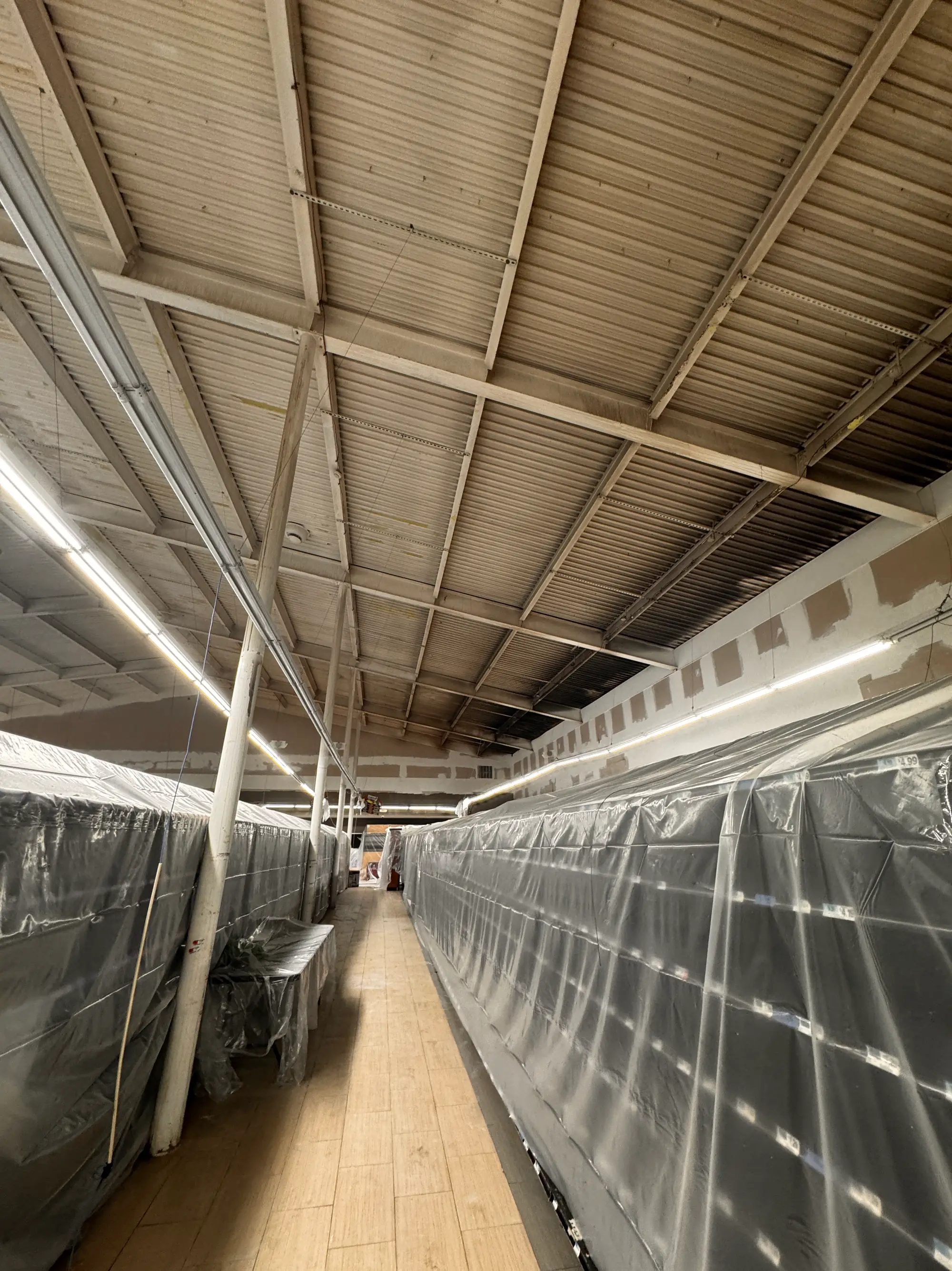 Long aisle of plastic-wrapped shelving protected during a commercial restoration job